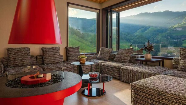 Una sala de estar moderna con chimenea, asientos cómodos y un amplio ventanal con vistas panorámicas.