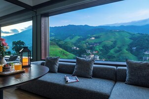A modern room with a large window offering a view of green hills and buildings.