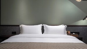 Una cama bien hecha con sábanas blancas, un edredón beige con textura y dos almohadas blancas.