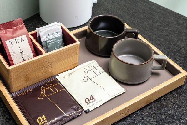 Una bandeja con bolsitas de té, una bolsita de café, una taza y una caja con la etiqueta 'ANNLAND'.