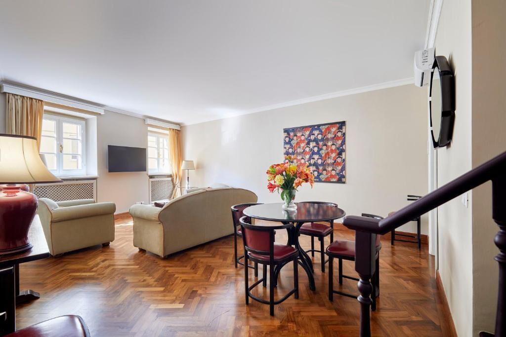 A living room with a sofa, a dining table with chairs, a TV, and a painting on the wall.