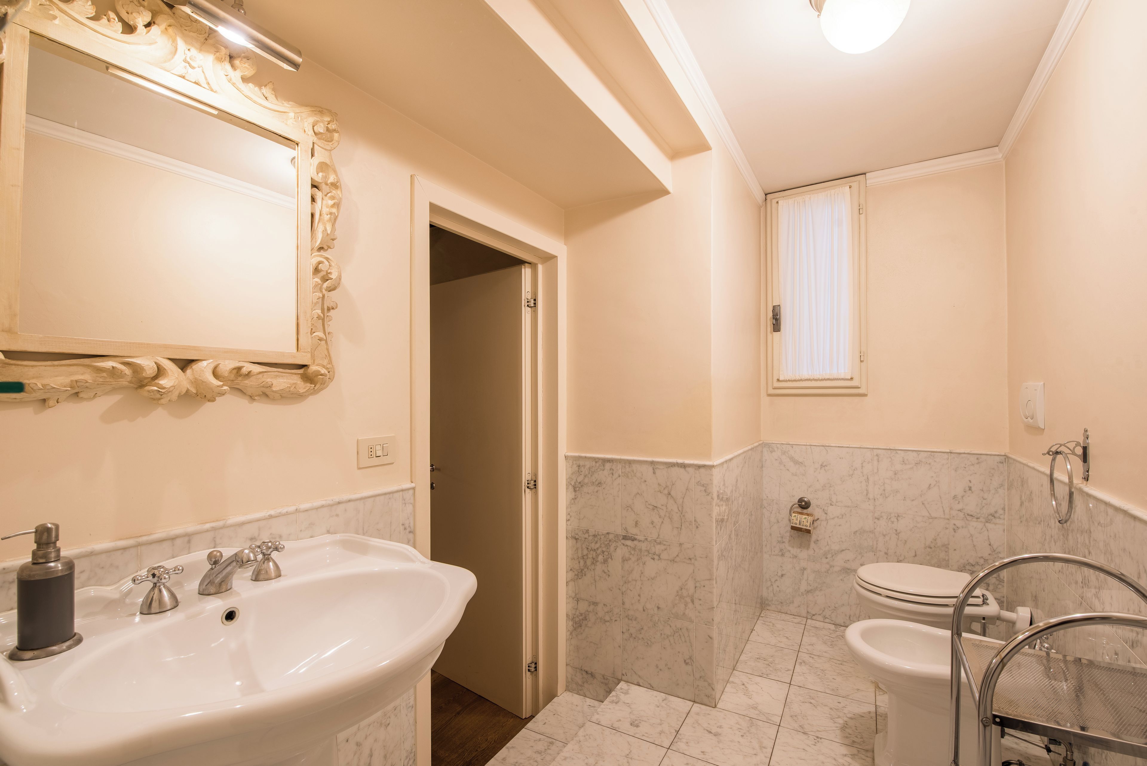 Ein Badezimmer mit großem Spiegel, Waschbecken, Toilette und Duschbereich.