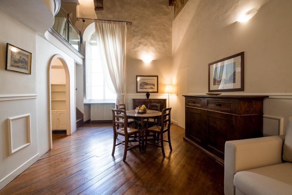 Ein Essbereich mit Holztisch und -stühlen, einem Kamin und einer Treppe, die in eine obere Ebene führt.