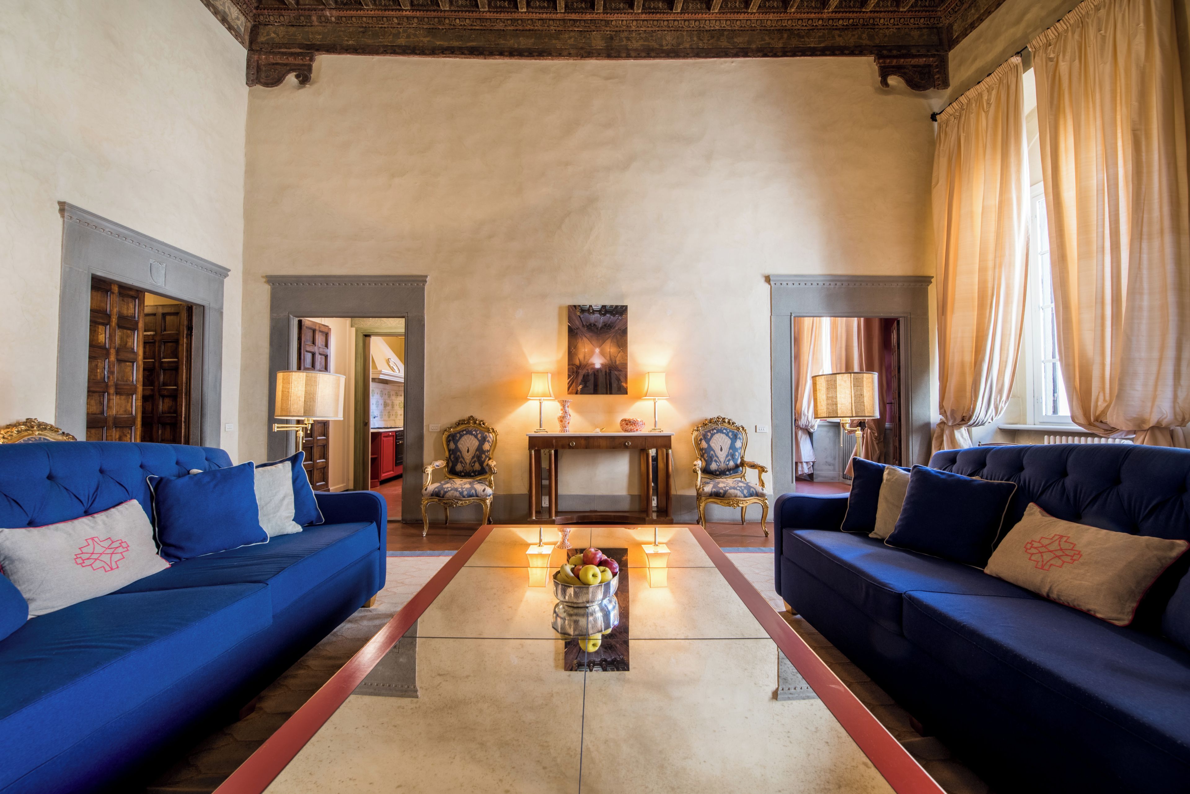 Un salón espacioso con dos sofás azules, una mesa de centro con fruta y una chimenea.