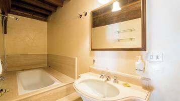 A bathroom with a bathtub, a sink, and a mirror.