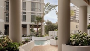 A modern hotel courtyard with a pool, palm trees, and a wooden deck. - The Lagoon, Main Beach (Main Beach)