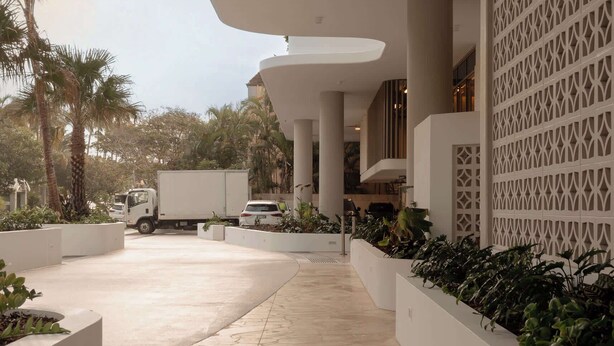 A modern building with a covered walkway, palm trees, and a truck parked outside. - The Lagoon, Main Beach (Main Beach)