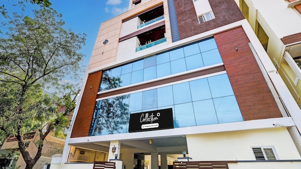 A modern building with a glass facade, a visible company sign, and a tree in the foreground. - Super Collection O Vanasthalipuram (Hyderabad)