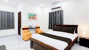 A hotel room with a bed, a desk, a chair, an air conditioning unit, and a painting on the wall. - Super Collection O Vanasthalipuram (Hyderabad)