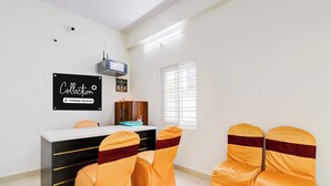 A conference room with a whiteboard, a desk, and four chairs with orange covers. - Super Collection O Vanasthalipuram (Hyderabad)