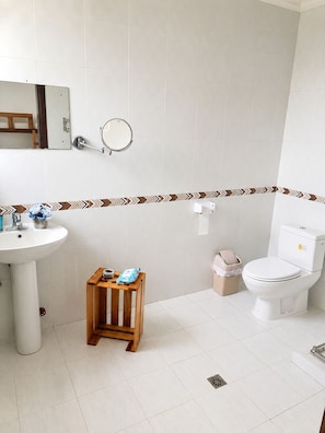Habitación cuádruple familiar, vista al jardín | Baño | Regadera y papel de baño 