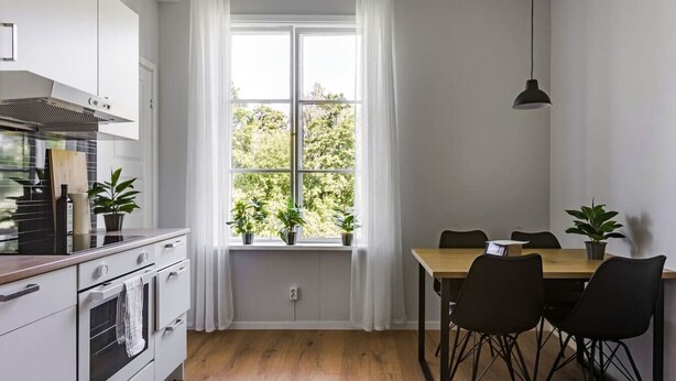 A modern kitchen with white cabinets, a stove, and a dining area with a table and chairs. - Peaceful Stay near Uppsala - Near Forests & Nature (Österbybruk)