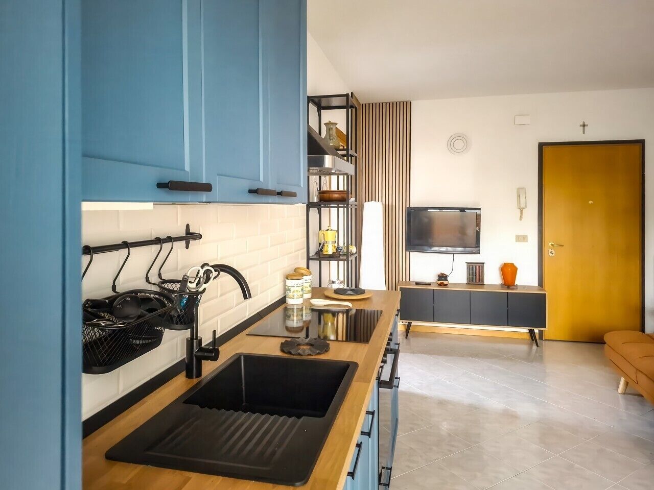 Eine moderne Küche mit einem schwarzen Spülbecken, einer Holzarbeitsplatte und blauen Schränken.