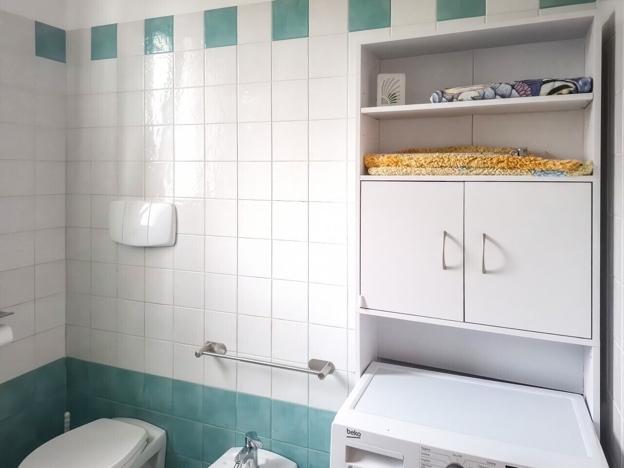 A bathroom with a toilet, sink, and cabinet.