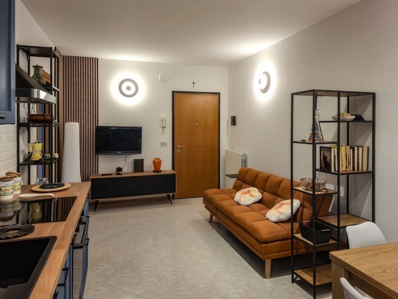 Uma sala de estar moderna com um sofá, uma TV, uma mesa de jantar de madeira e uma estante de livros.