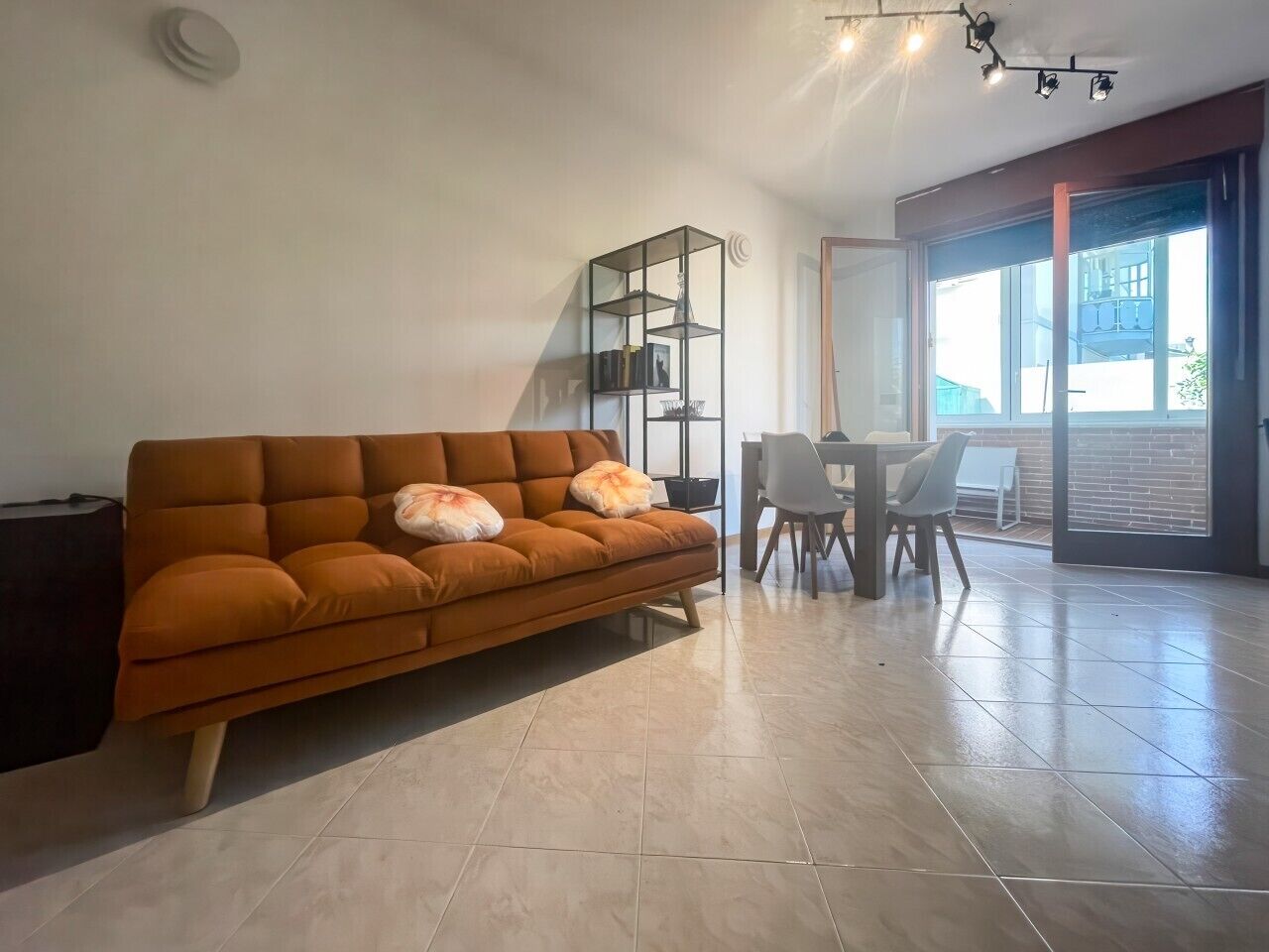 Ein modernes Wohnzimmer mit einer Couch, einem Esstisch mit Stühlen und einem großen Fenster.