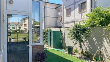 Il s’agit d’une propriété résidentielle dotée d’une cour arrière clôturée, d’un abri de jardin vert et d’une porte visible donnant accès à un espace extérieur abrité.