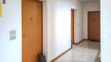 Ein Korridor mit Holztüren, einem Mülleimer und einem Lichtschalter an der Wand.