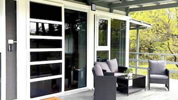 A covered outdoor area with a sliding glass door, wicker furniture, and a welcome mat.
