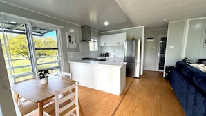 A modern kitchen with white cabinetry, a central island, and a stainless steel refrigerator. - Country Coast Retreat - newly built cabin on acreage, 12 min drive to the beach (Failford)