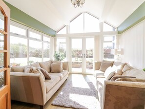 A spacious room with a high ceiling, large windows, and a view of the outdoors. - Ger Y Mor (Cemaes Bay)