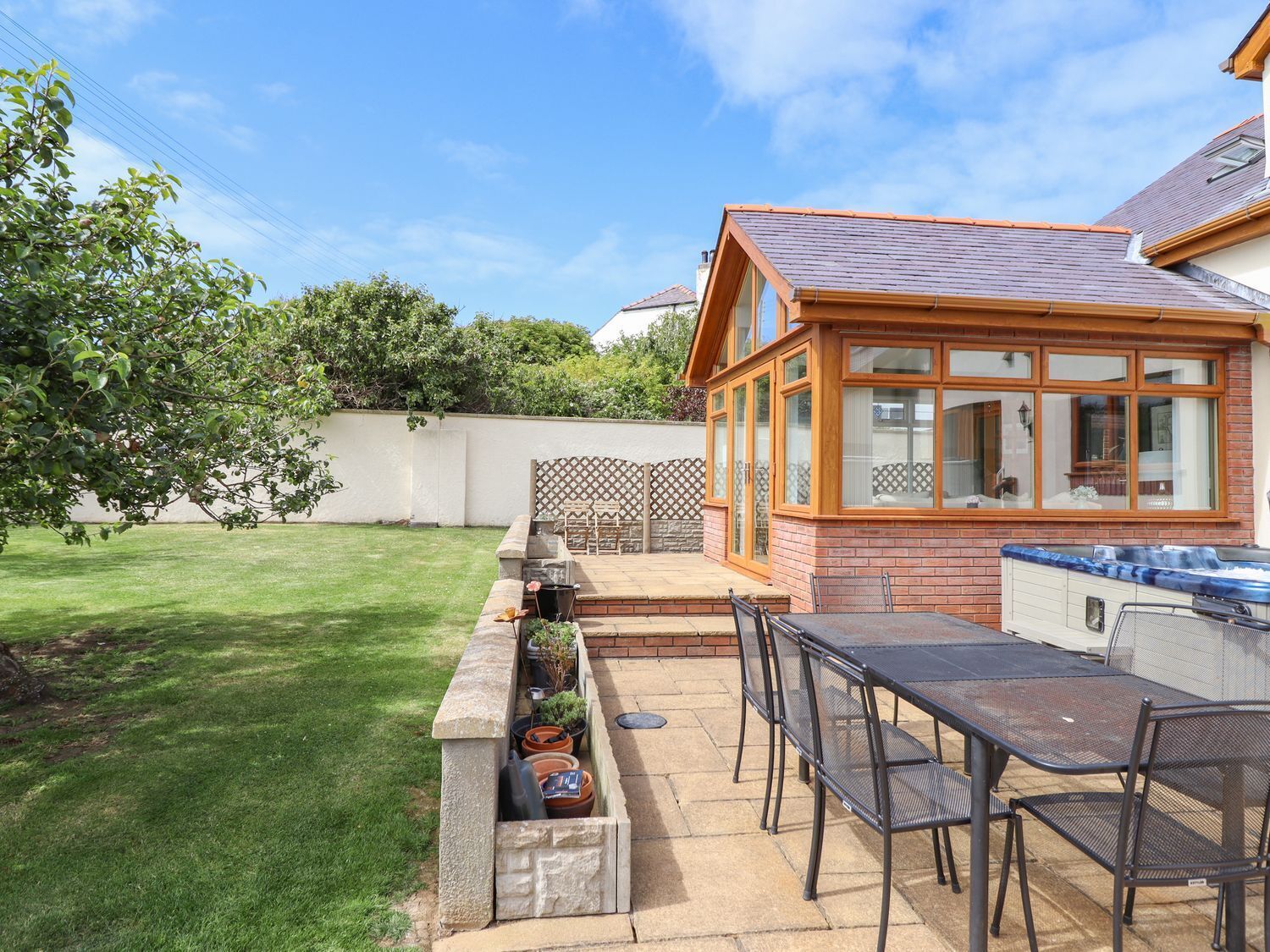 Een terras met een barbecue, zitplaatsen en een hottub.