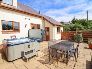 Ein Whirlpool in einem Hinterhof mit einem Patio-Tisch und Stühlen.