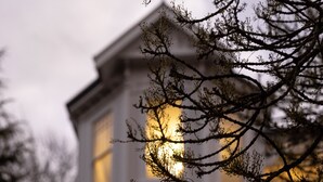 Ein zweistöckiges Haus mit weißer Fassade und zahlreichen Fenstern.