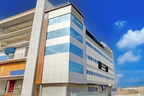 Un edificio de varios pisos con un diseño arquitectónico moderno, que presenta un cartel llamativo para un servicio de empresa.