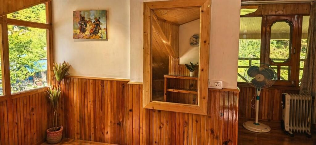 Ein Zimmer mit Holzwänden, einem Blumentopf, einem Bild an der Wand und einem Ventilator.