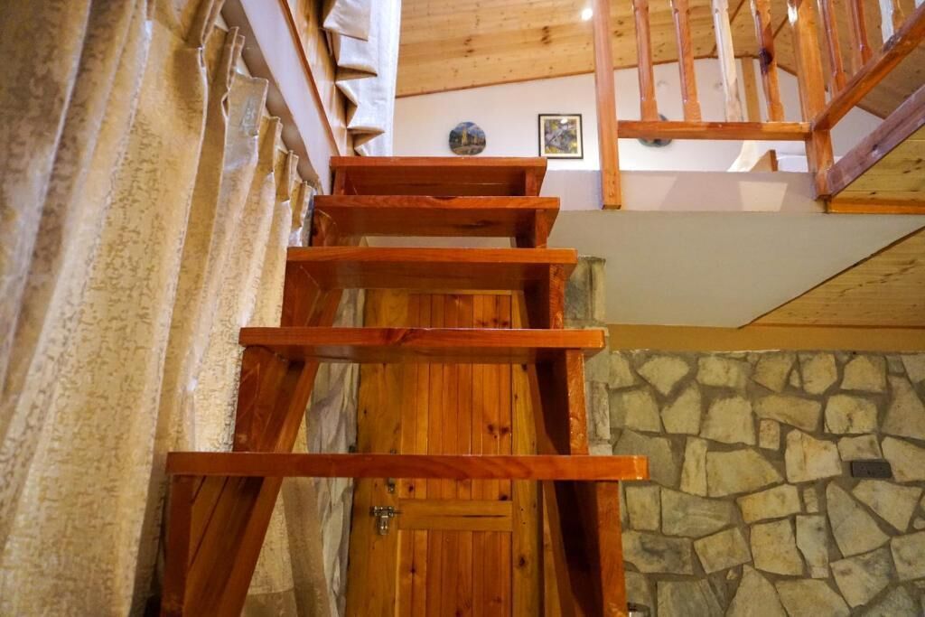 A wooden staircase with a stone wall and a wooden door at the bottom.