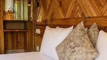 Cabecera de madera con diseño en espiga, cama con ropa de cama blanca y dos almohadas con textura.