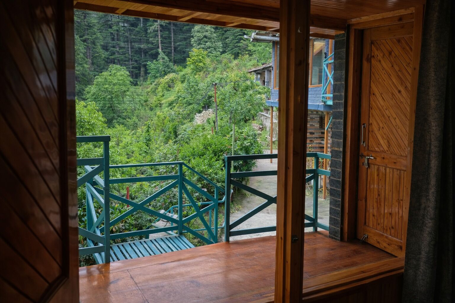 A wooden balcony with a view of a forested area.