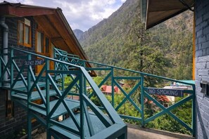 Una cabaña de madera con una escalera que conduce a un balcón, rodeada de un paisaje montañoso.