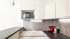 Een moderne keuken met een ingebouwde magnetron, een koffiezetapparaat en een spoelbak.