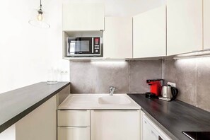 A modern kitchen with a built-in microwave, a coffee maker, and a sink. - Elegant apartment near Place Vendôme - 1 bedroom - long stay - Madeleine I by Habitat Parisien (Paris)