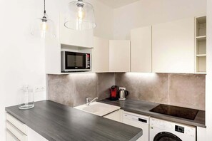 Een moderne keuken met een magnetron, koffiezetapparaat en wasmachine.