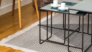 Een moderne woonkamer met een blauwgroene fauteuil, een grijze bank, een klein rond bijzettafeltje en een vloerlamp.