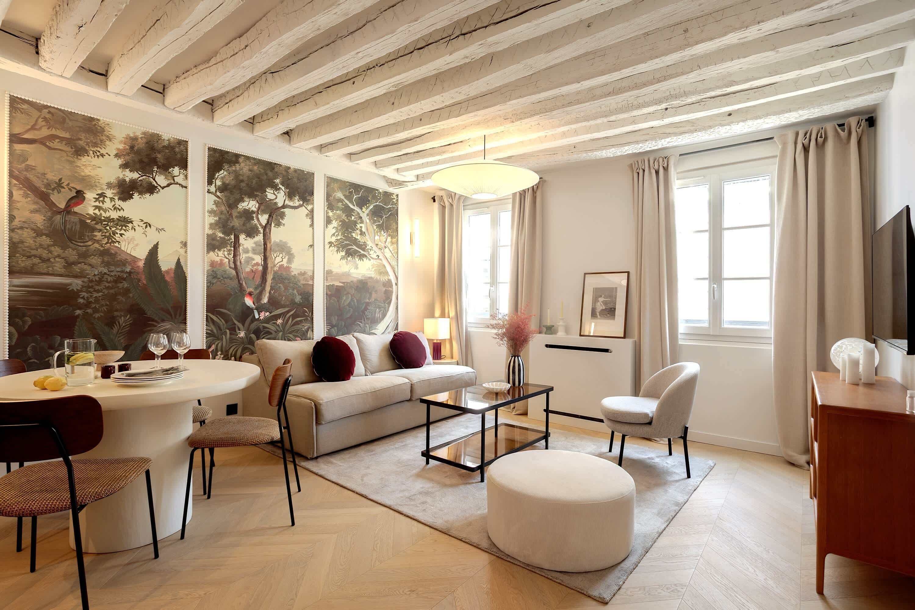 A modern living room with a sofa, coffee table, and chairs, a dining area with a table and chairs, and a large painting on the wall.