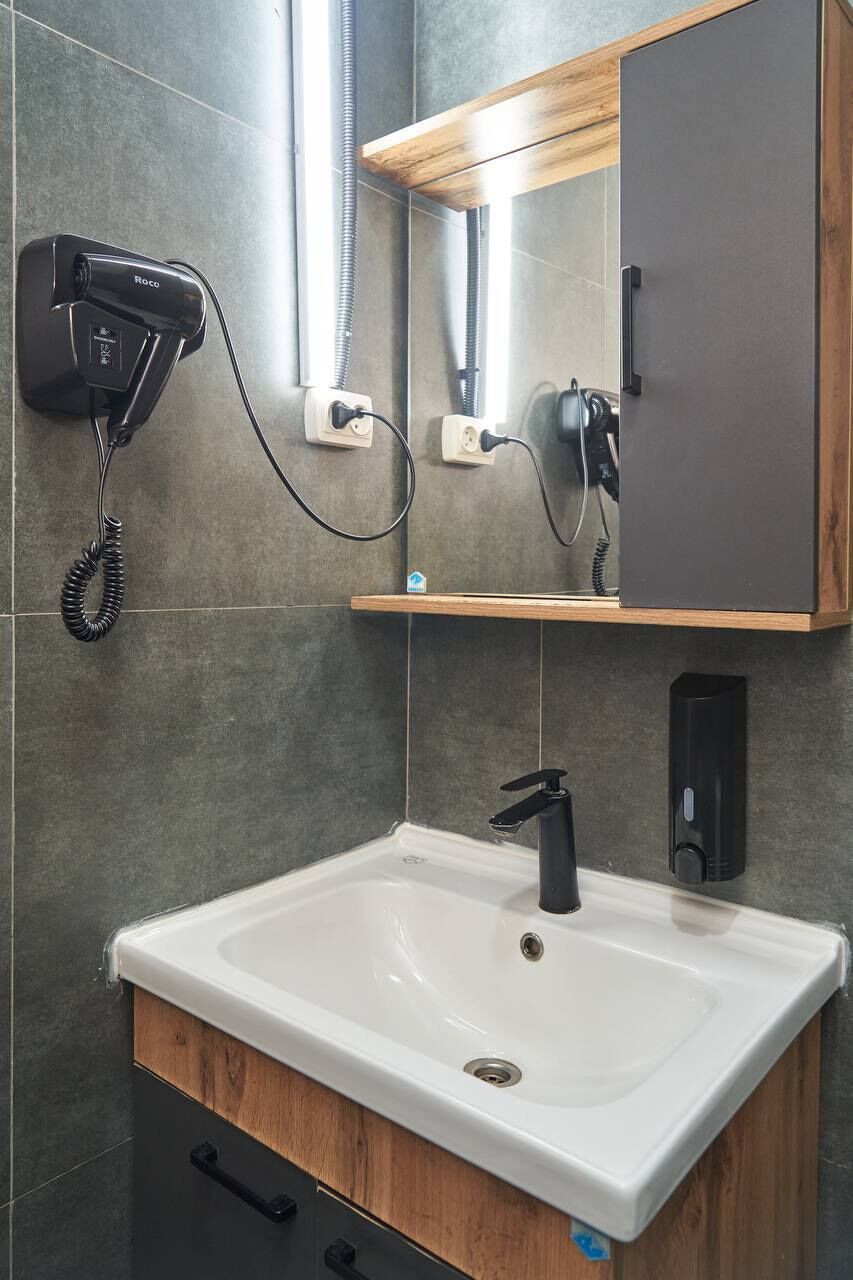Un baño moderno con lavamanos blanco, secador de pelo y espejo encima.