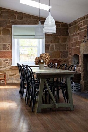 A dining area with a stone wall, a wooden table, and chairs.
