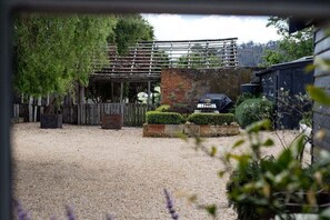 A gravel courtyard with a wooden fence, a brick wall, and a metal structure.