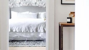 Una puerta que da a un dormitorio con una cama, una lámpara de pared y un cuadro en la pared.