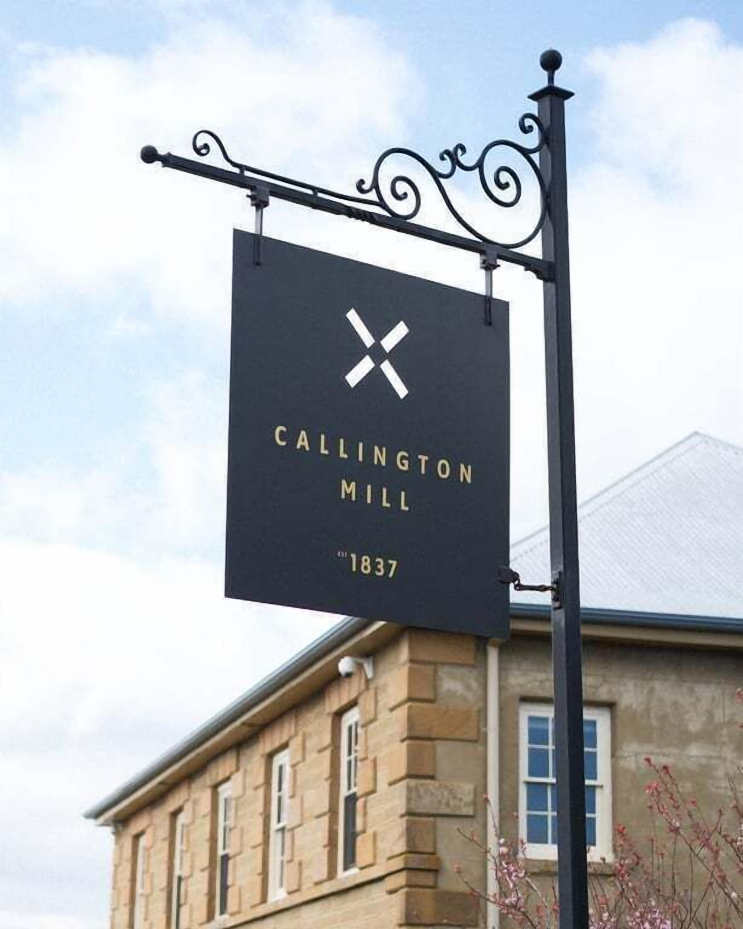 En skylt för Callington Mill, en historisk byggnad med en fasad av sten och traditionell fönsterdesign.
