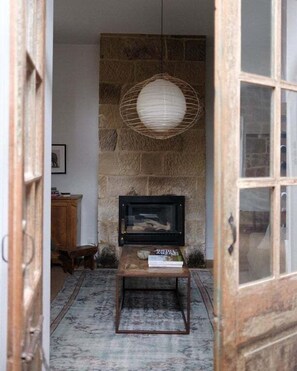 A room with a stone wall, a television on a stand, a wooden door, and a hanging light fixture.