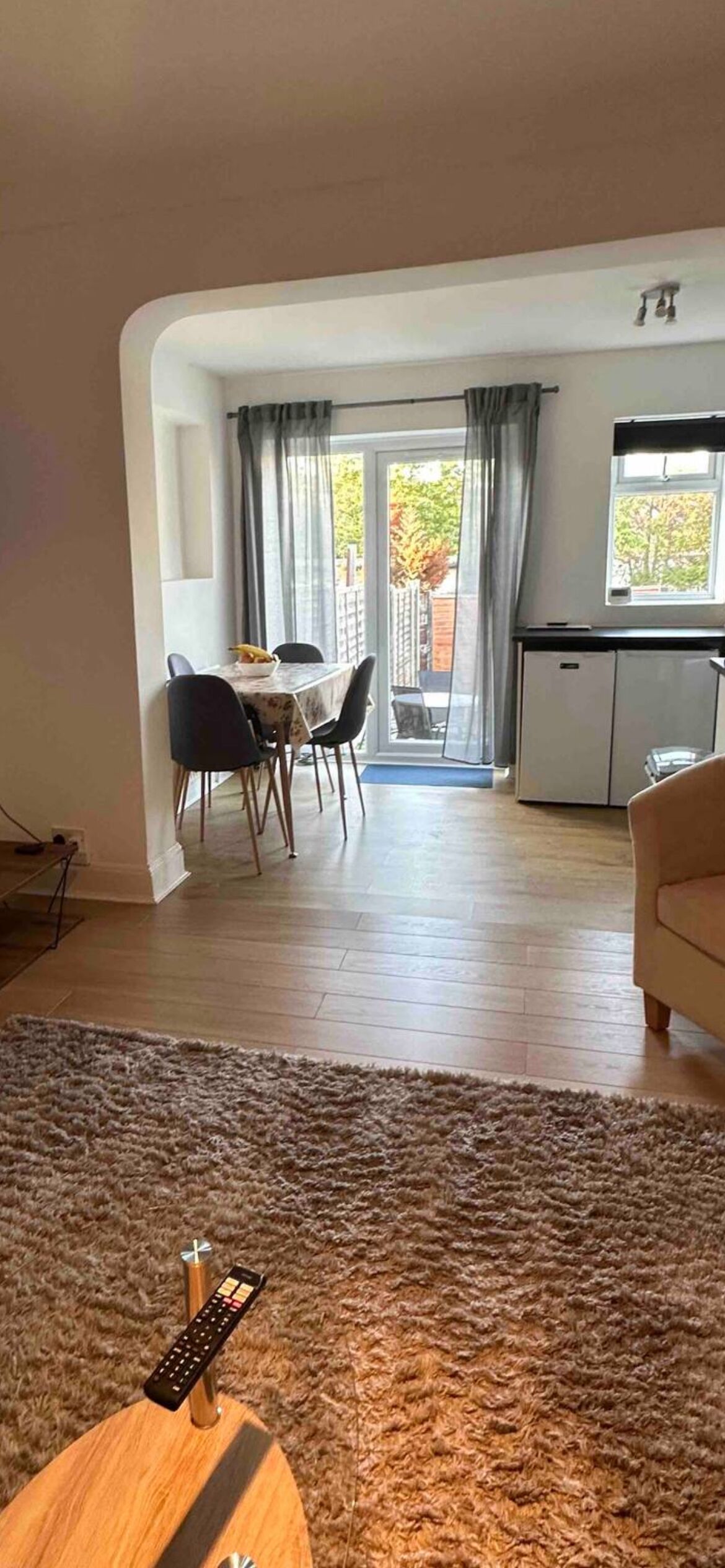 Un salon avec un canapé, une table basse et une télécommande posée dessus.
