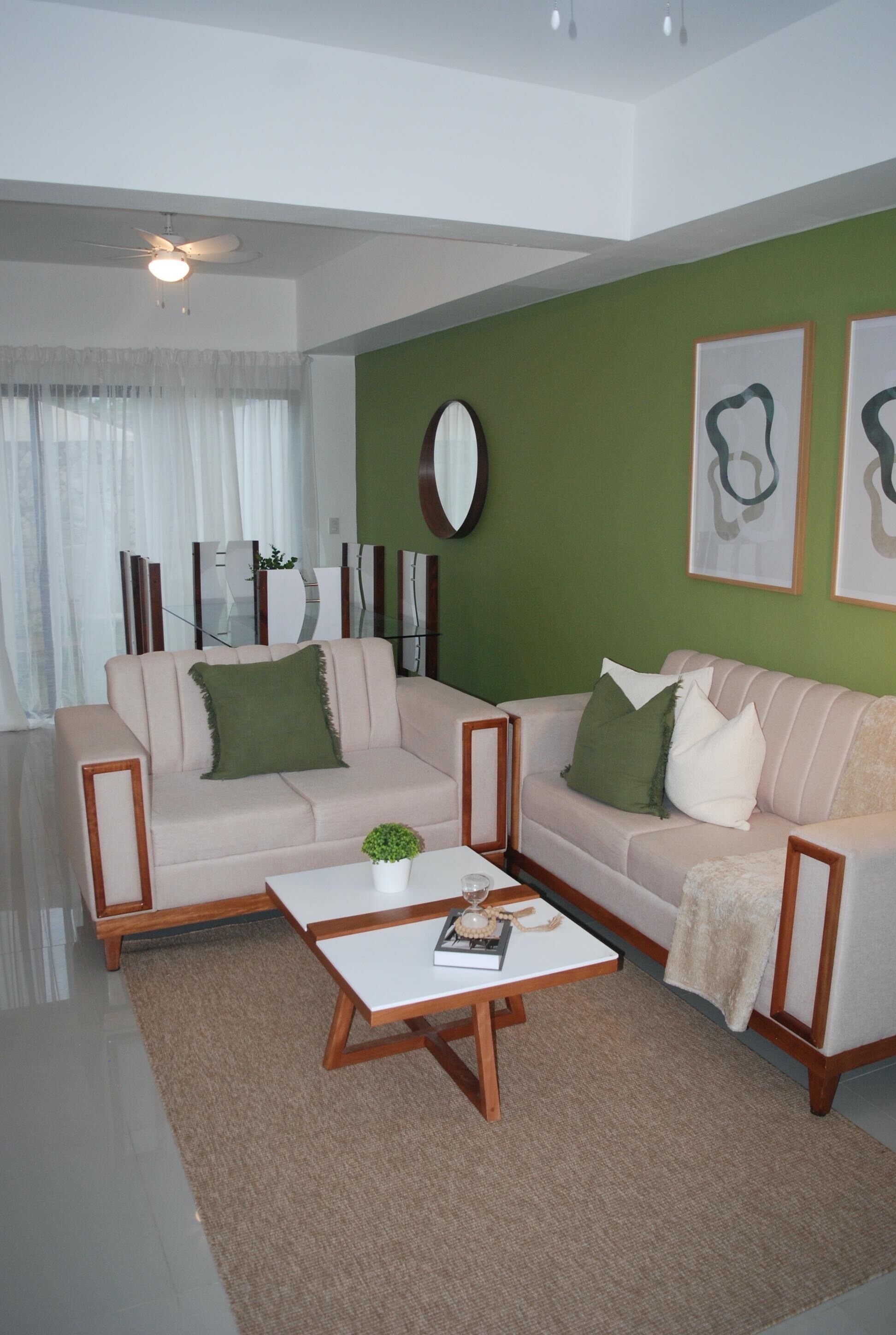 Ein Wohnzimmer mit zwei Sofas, einem Couchtisch und einer Wand in Grünton.