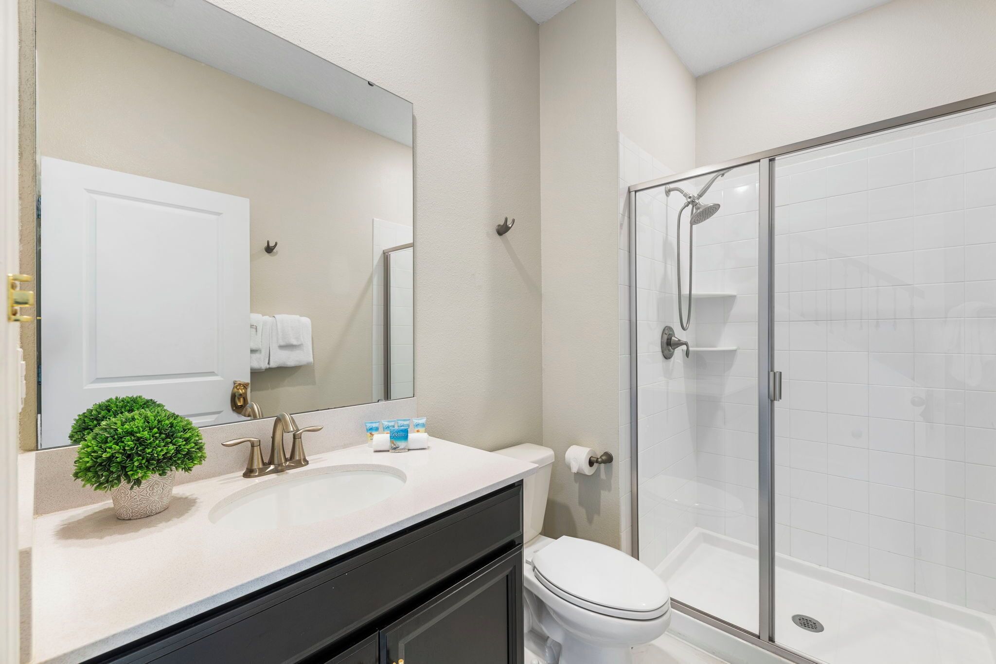 A modern bathroom with a white sink, a toilet, and a glass-enclosed shower.