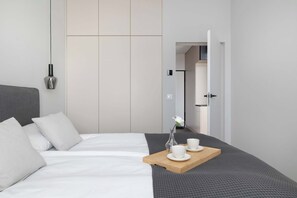 A modern hotel room with a bed, bedside table, and a view of the hallway. - Stylish Apartment | Underground Parking | Close to Spodek Arena (Katowice)