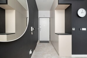 A modern hallway with a round mirror, a door, and a wall-mounted clock. - Stylish Apartment | Underground Parking | Close to Spodek Arena (Katowice)